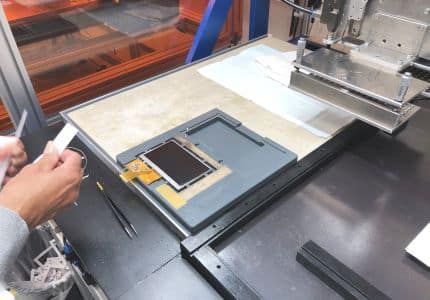 Employee sets up touchscreen for optical bonding