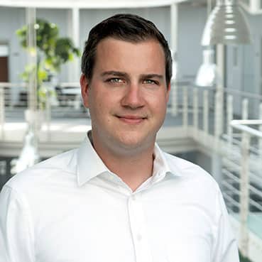 A happy office worker with a smiling expression, in an overshirt, with forehead, eyebrow, jaw, sleeve and collar visible.