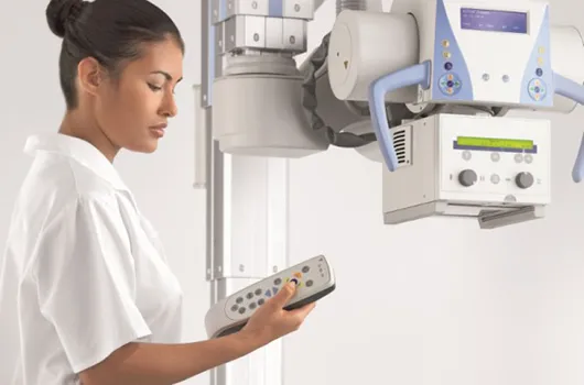 Woman holds remote control for X-ray machine in hand