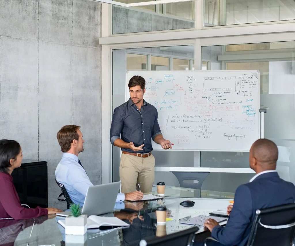 Employees discuss a project on the whiteboard