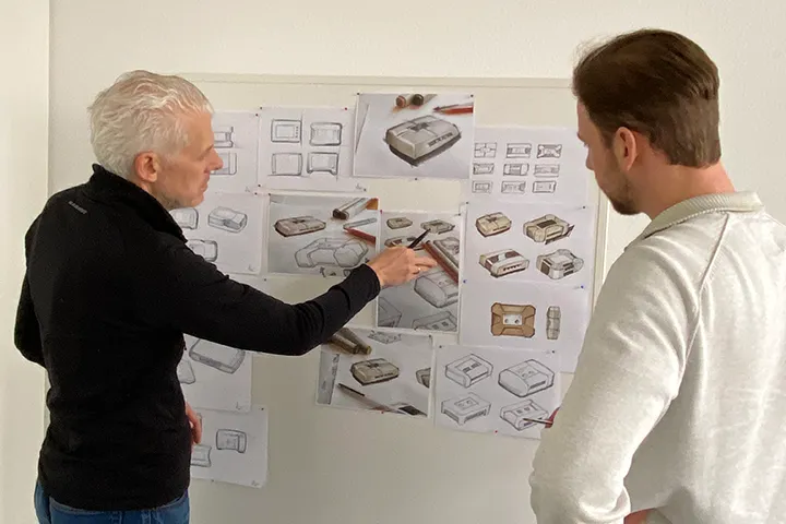 Employees discuss product design on whiteboard