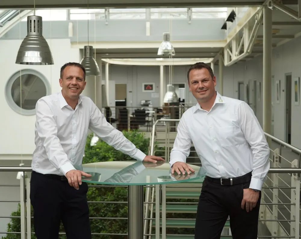Two executives from Hoffmann + Krippner at a bar table in the company building