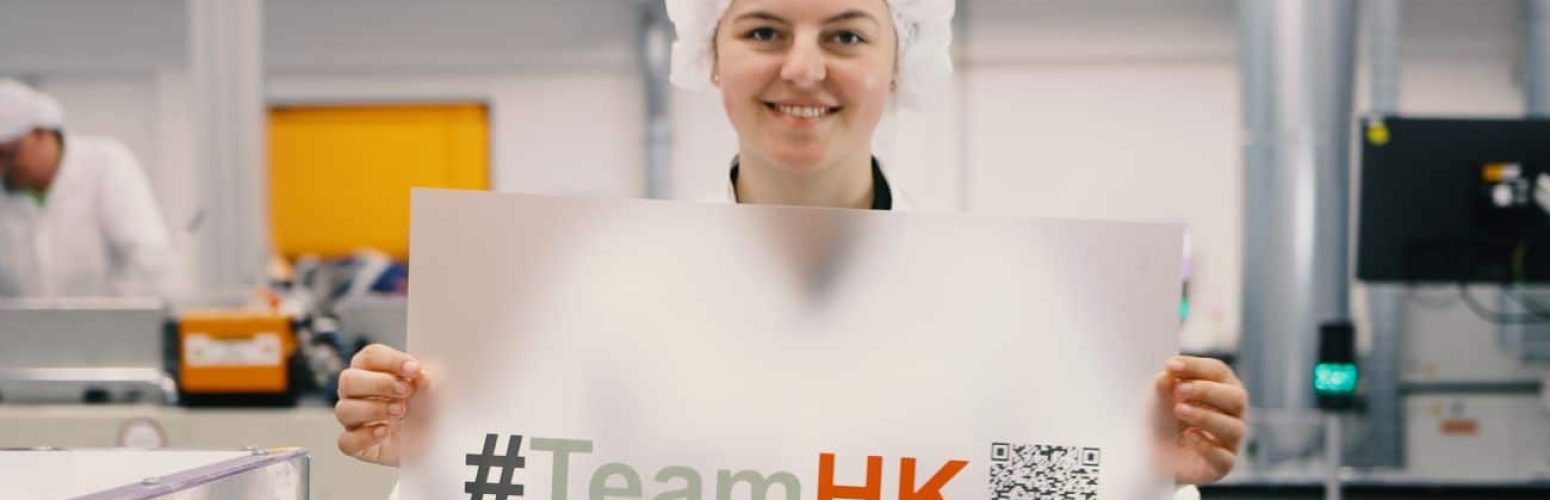 Hoffmann + Krippner - Employee lifts printed film with #TeamHK into the camera